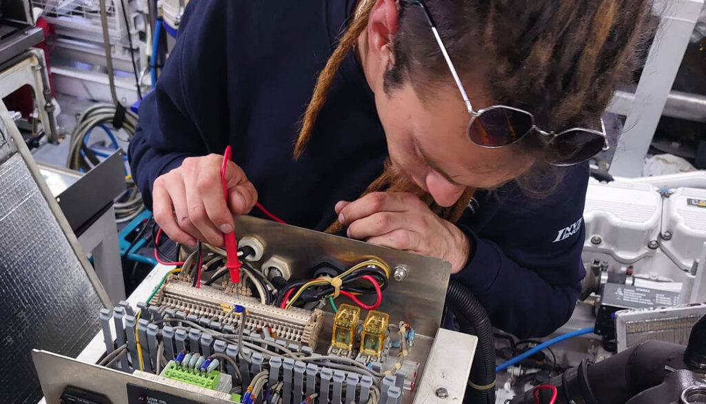 Smart Yachts International team member working on electrics in yacht engine room